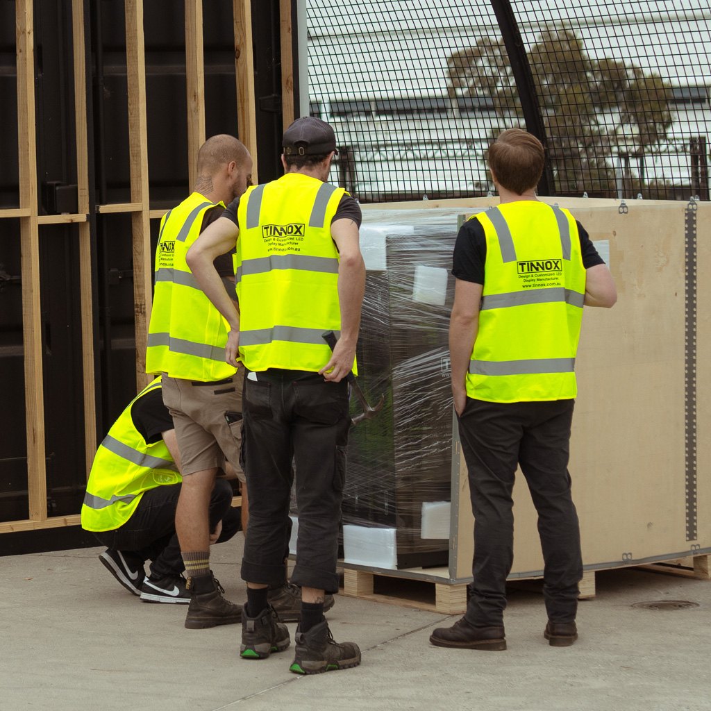 TINNOX technicians in high-visibility vests around a shipped LED display