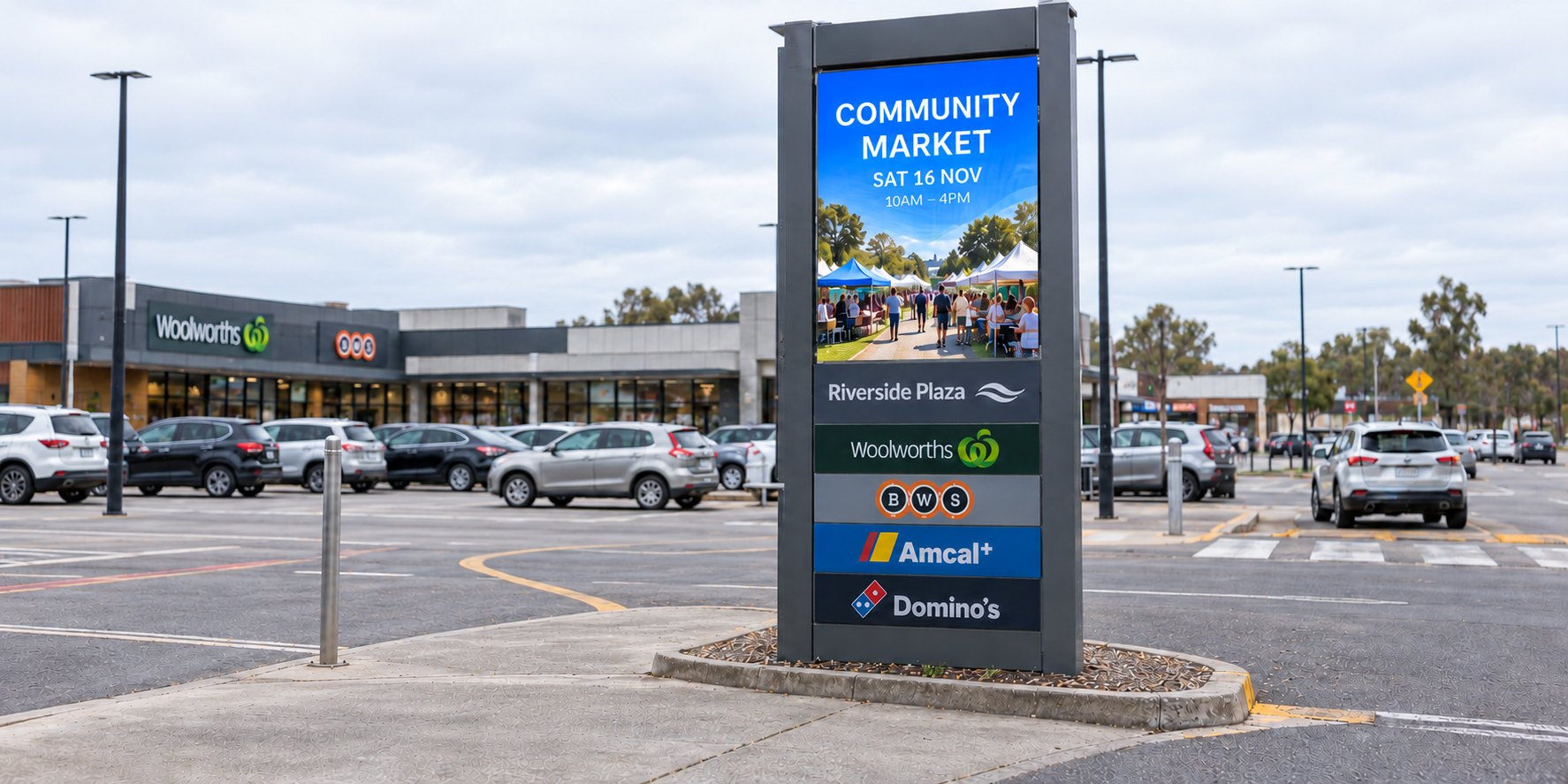 A DuraBlaze electronic sign set into a shopping plaza pylon beside the car park, showing a community market notice